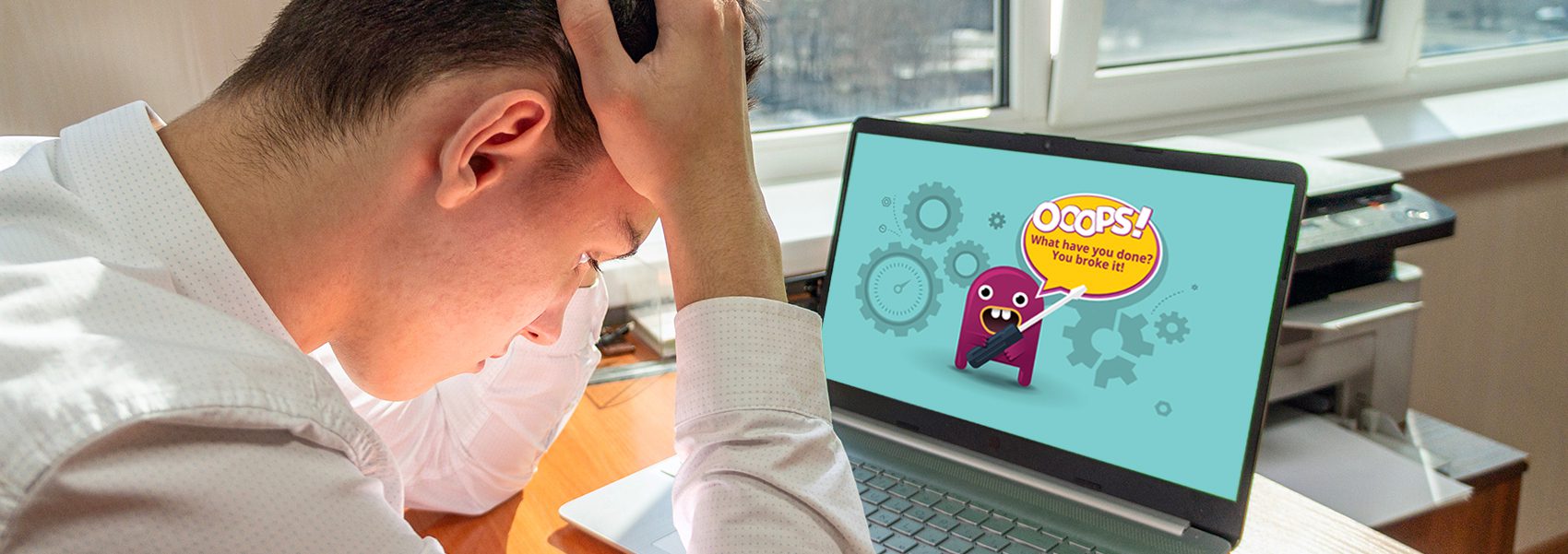 Young man holding his head in front of a laptop screen with an error message.
